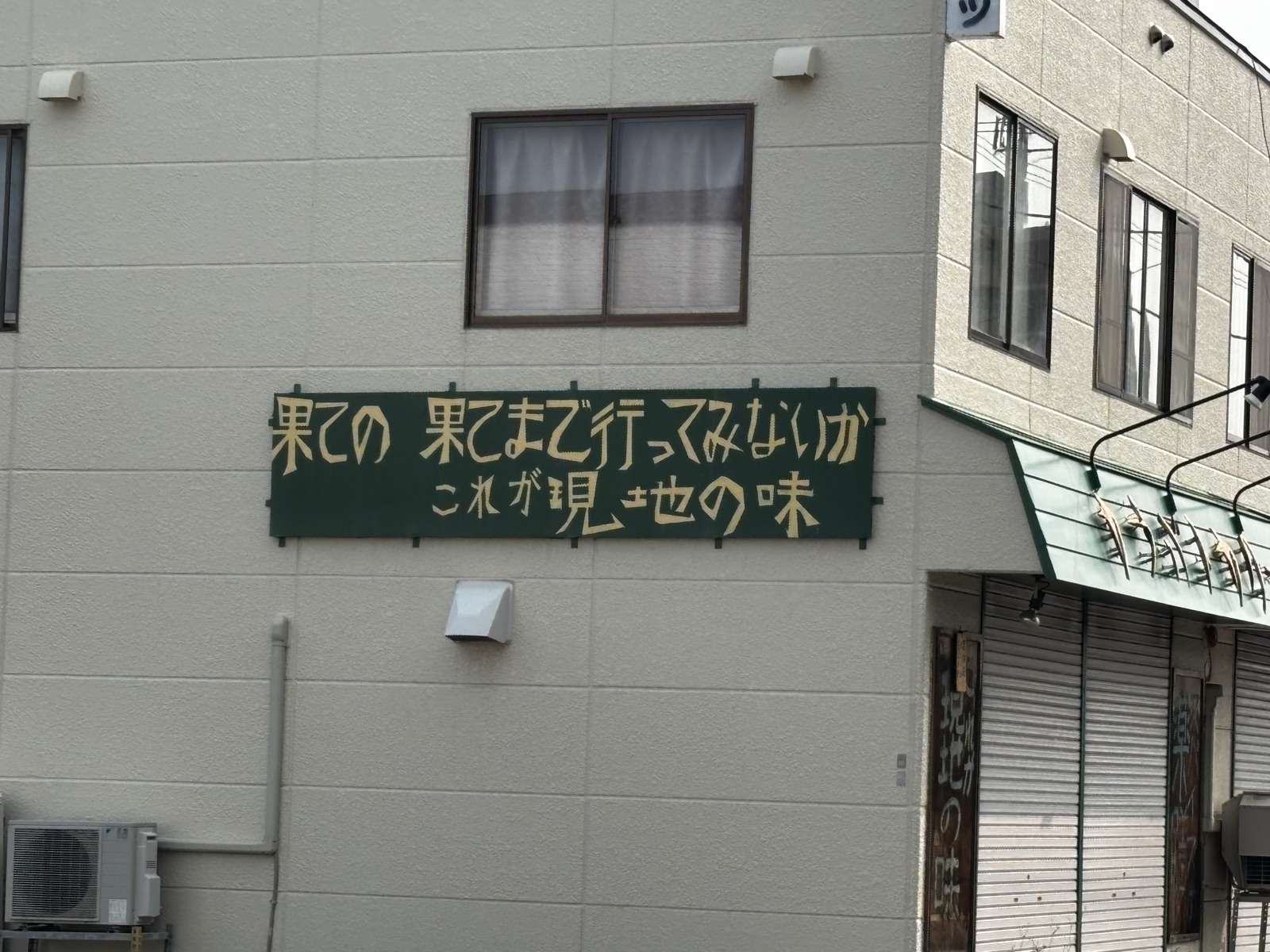 カラバトカリーの壁の看板。「果ての果てまで行ってみないか これが現地の味」と書かれている